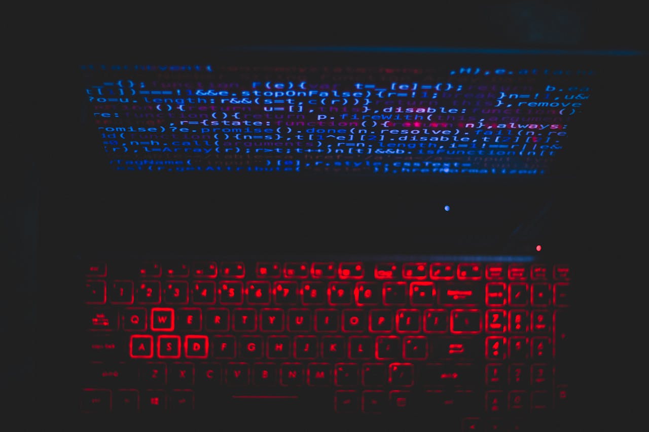 Home Dark-themed laptop setup with a red glowing keyboard and code on screen, ideal for tech enthusiasts.